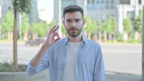 Outdoor Portrait of Young Man with Ok Sign