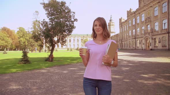 Woman with Notebooks Drinking Tea Walks in Campus Area