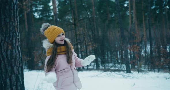 Small Girl Plays Smiling Snowballs with Family in Forest