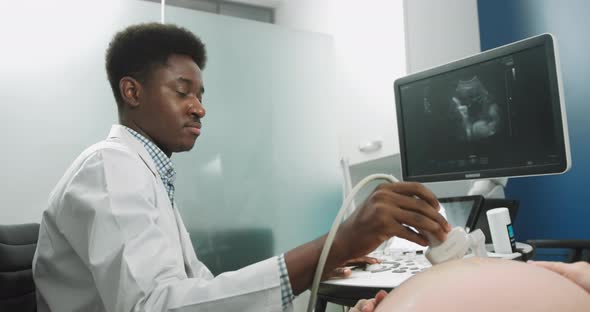 Young Professional Male African Doctor Looking at the Screen While Performing