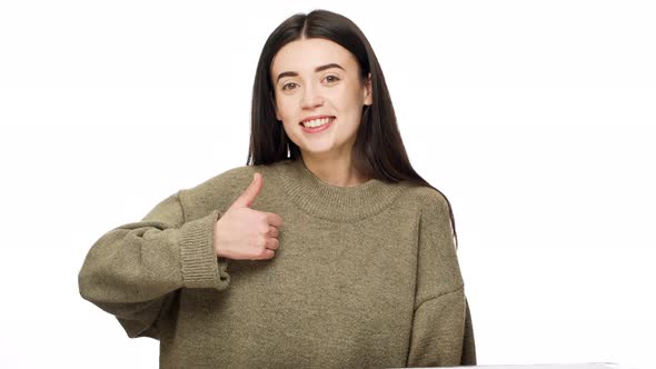 Portrait of Adorable Woman 20s with Long Dark Hair Expressing Approval with Gesturing Thumb Up Over