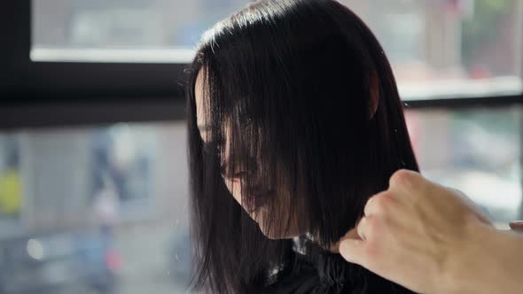 Hairdresser Cutting Client's Hair in Salon with Scissors Closeup