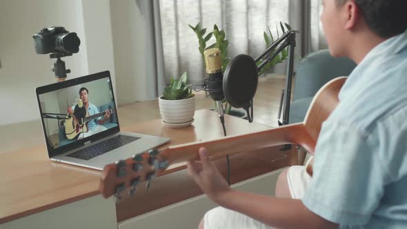 Boy Playing Guitar And Sing A Song While Streaming On Computer Laptop