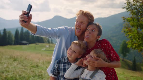 Playful Family Grimacing Selfie on Smartphone Standing Mountain Slope Close Up