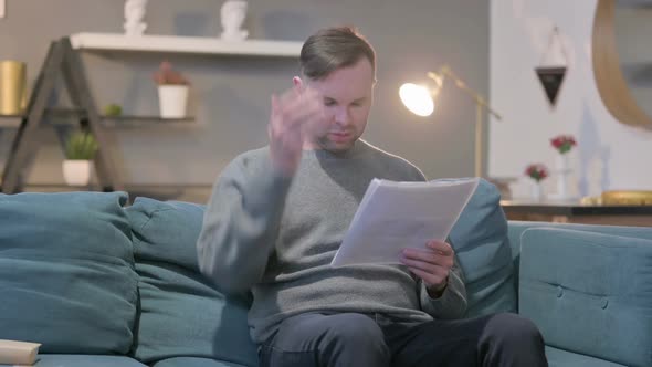Casual Man Reacting to Loss on Documents Sofa