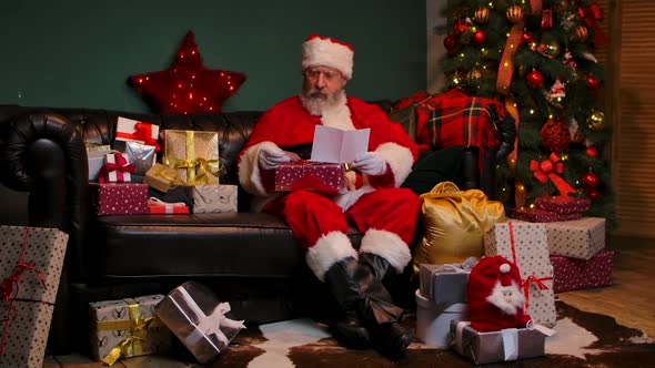 Santa Claus Reads Letters and Puts in Bag Gifts for Children