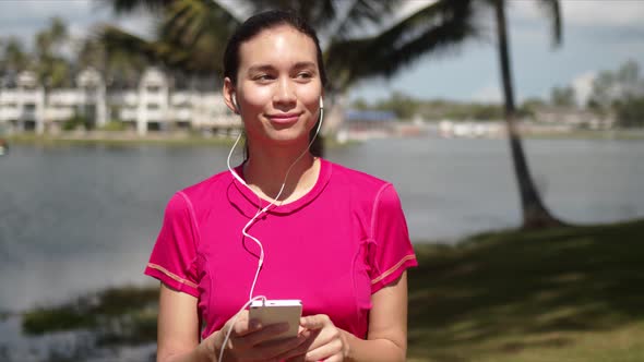 Casual Woman Listening To Music on Smartphone on Lakeside