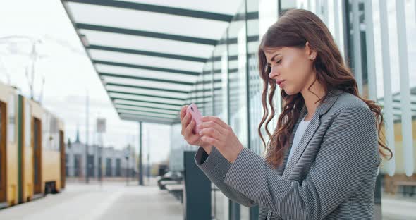 Young Beautiful Woman Holding Her Smartphone in Horizontal Landscape Mode and Touching Screen