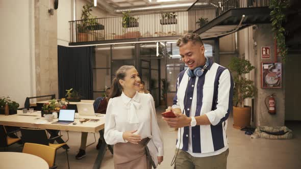 Coworkers browsing smartphone near colleague