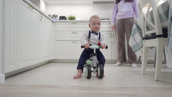 Mother and Baby Boy Play on the Floor Mother Teaches 1 Year Old Child to Ride a Balance Bike