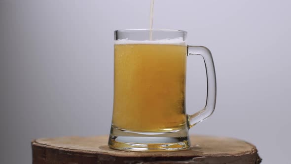 Slow Motion Shot of Light Beer Is Poured Into a Beer Glass with a Handle, a Lot of Bubbles and Foam