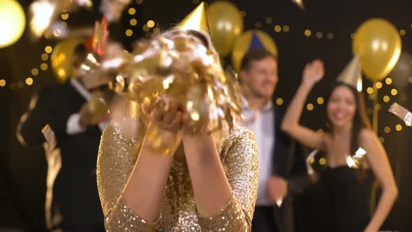 Smiling Young Woman Blowing Gold Confetti Sending Air Kiss on Camera, Happiness