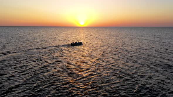 A boat sailing on the sea, early in the morning, beautiful sunrise as background