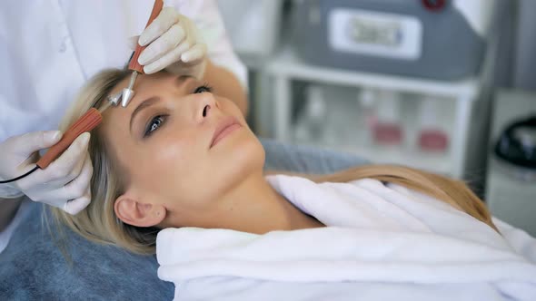 Closeup of Beautiful Woman Receiving Facial Microcurrent Treatment From Therapist at Beaty Salon