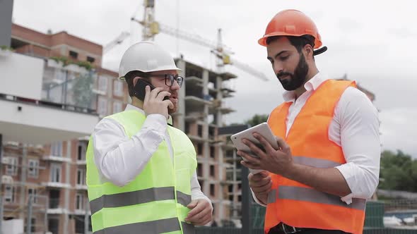 Engineer Speaks on Mobile Phone on Construction Site and Checks the Work of the Worker. Builder