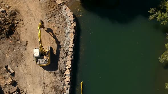 A large excavator repairing a section of river damaged by a flood waters caused by a tropical cyclon