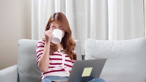 Young woman enjoying a cup of tea while using notebook to chat with friends.