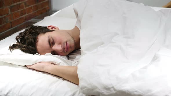 Young Man Sleeping on Side in Bed at Night