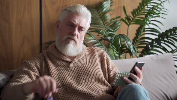 An Elderly Man Is Sitting Alone on the Couch a Patient Is Wearing Glasses Reading Instructions on a