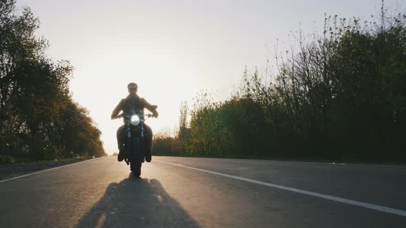 Motorcyclist Surfing on Hugh Speed on His Motorbike on the Road in Sun Beams