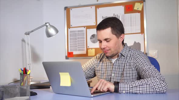 A Satisfied Man Looks at the Laptop Monitor and Writes a Message To a Friend