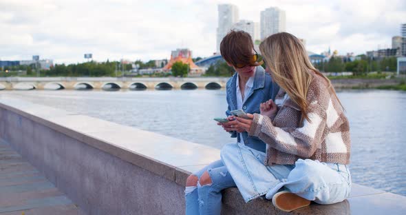 Normal Life of a Lesbian Couple Women Sit in an Urban Environment Surf on Their Phones and