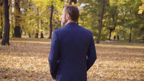 A Middleaged Handsome Caucasian Man Looks Around As He Walks in a Park in Fall