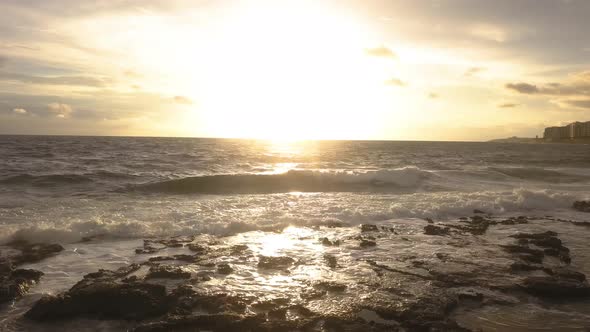 Low angle view of sunrise on the horizon over the Mediterranean Sea. Flying out over the surf past t