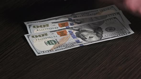 Counting New Hundred Dollar Banknotes on a Black Wooden Table