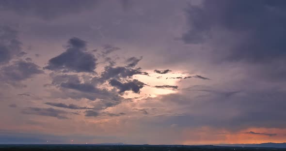 As a Dramatic Lightning Storm Crosses the Sky During a Thunderstorm a Brilliant Orange Sunset