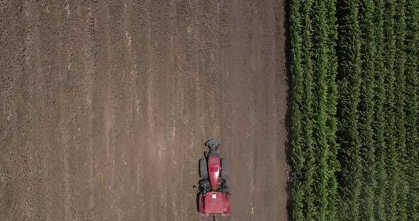 Red tractor flattening a field for seeding, Drone follow footage.