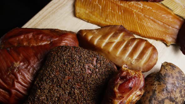 Rotating shot of a variety of delicious, premium smoked meats on a wooden cutting board 