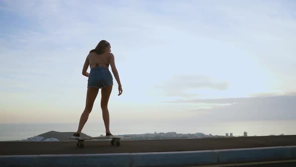 Girl Riding a Skateboard Near the Ocean and a Large Mountain in Slow Motion. Healthy Lifestyle