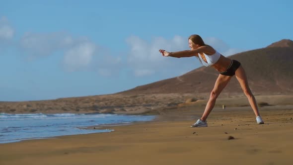Woman Stretching Legs and Hamstrings Doing Standing Forward Bend Yoga Stretch Pose on Beach