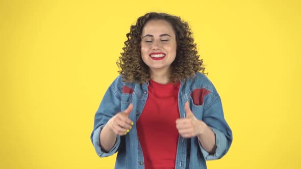 Young Cheerful Woman Showing Thumbs Up, Gesture Like, Over Yellow Background, Slow Motion