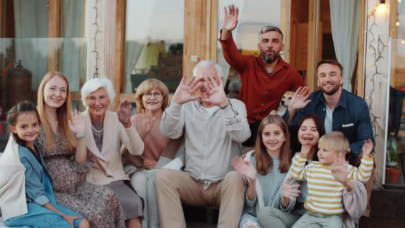 Joyous Caucasian Family Waving and Posing for Camera on Terrace