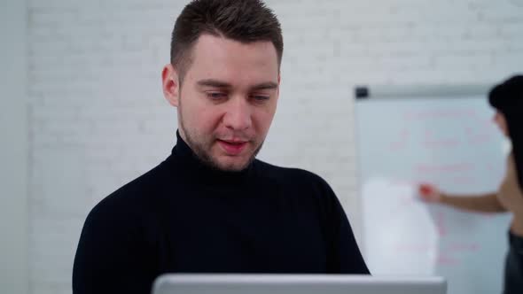 Man working with woman. Young businessman working against standing woman near board