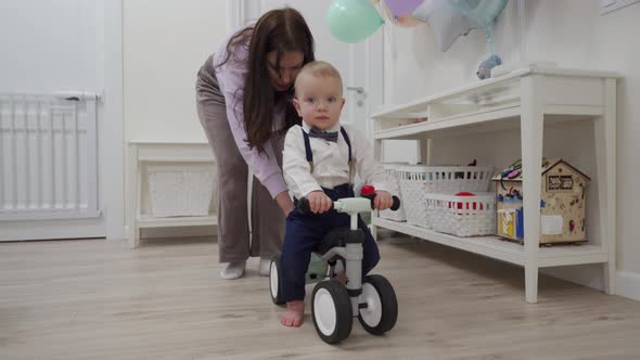 Mother and Baby Boy Play on the Floor Mother Teaches 1 Year Old Child to Ride a Balance Bike