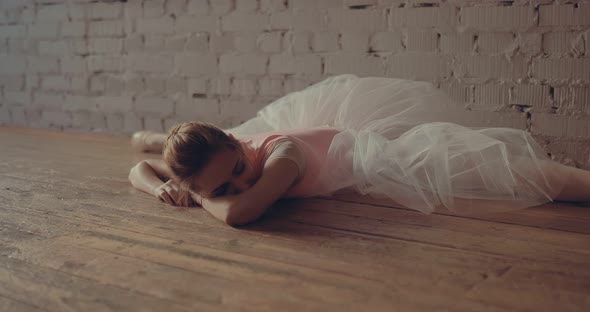 Ballerina Stretches Leg Muscles Lying in the Twine Against the Wall