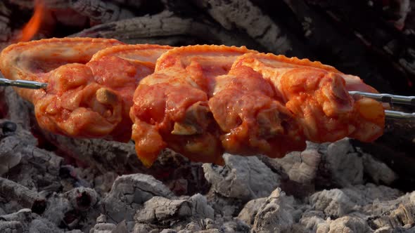 Closeup of Raw Chicken Wings on the Skewers Rasting and Frying Above Open Fire