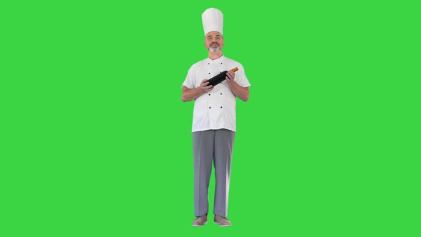 Smiling Male Chef Cook Holding a Bottle of Perfect Wine on a Green Screen, Chroma Key.