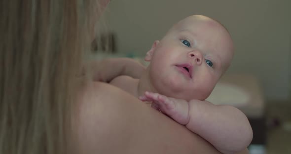 Perplexed Newborn Baby Boy Looks Around on Mother's Hands and Kisses Him