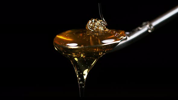 900374 Honey Flowing on Spoon against Black Background, Slow Motion 4K