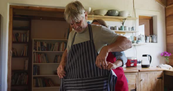 Smiling senior caucasian couple wearing aprons and preparing before cooking in kitchen