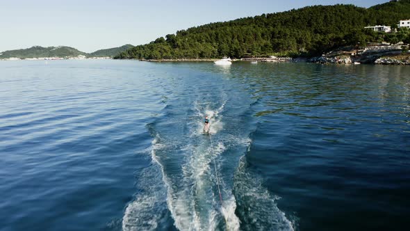 Drone view of kid doing water ski in the sea.