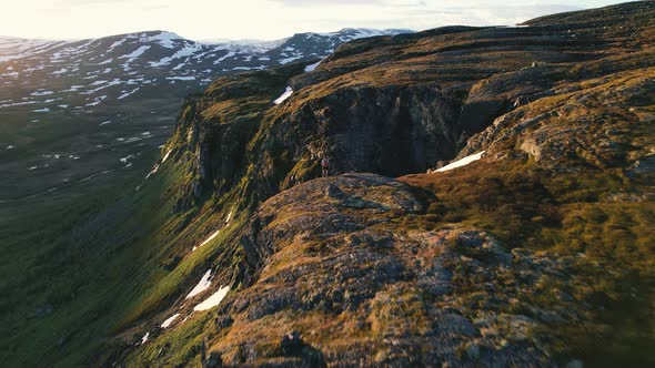 Aerial Along Sunlit Mountain Top Edge With Hiker Standing At Hardangervidda National Park, Eidfjord,