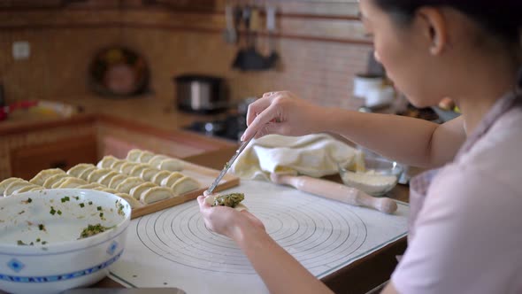 Female cook stuffing dough with meat