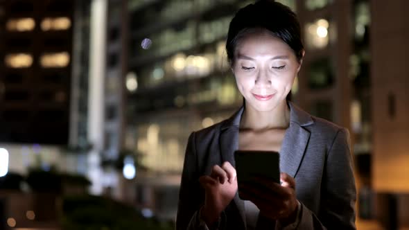 Business woman using smart phone in city at night 