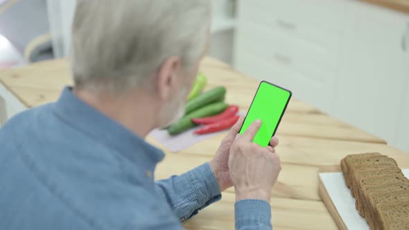 Rear View of Old Man Looking at Smartphone with Chroma Key Screen