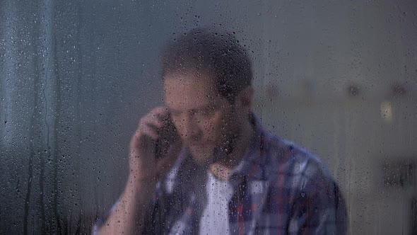 Middle-Aged Male Talking Phone With Family Behind Rainy Day, Missing Relatives